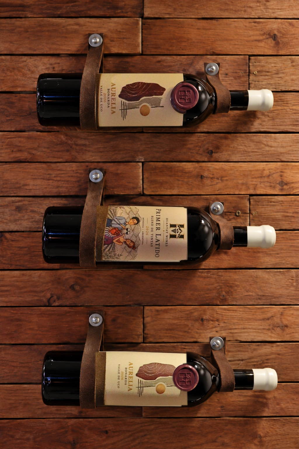 Tres botellas de Huantay Wines: dos Aurelia y una Primer Latido sobre una pared de madera